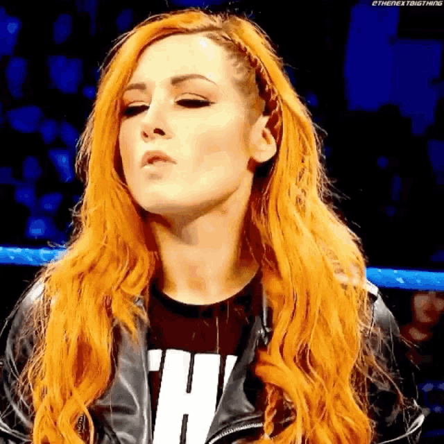a woman with red hair is wearing a black leather jacket and a black shirt with the letter h on it .