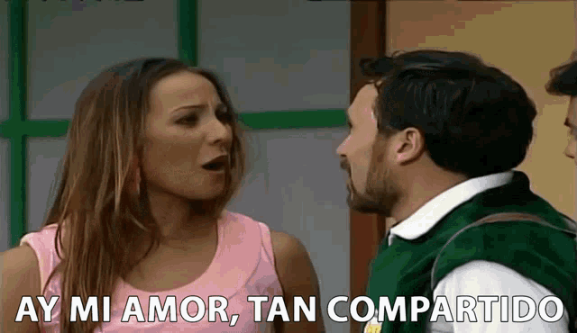 a woman in a pink tank top is talking to a man in a green vest while another man looks on ..