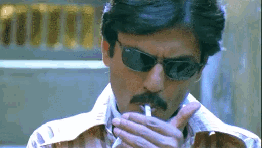 a man with a mustache wearing sunglasses smoking a cigarette