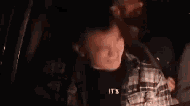 a man in a plaid shirt is sitting in the back seat of a car and laughing .