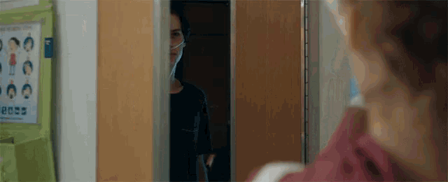 a man wearing an oxygen mask stands in a doorway