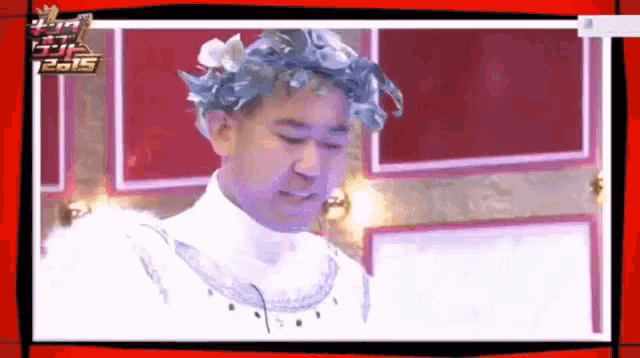 a man with a laurel wreath on his head is standing in front of a wall with the year 2015 on it