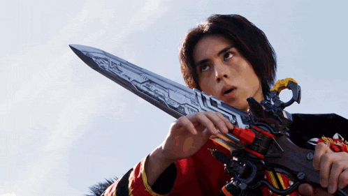 a young man is holding a large sword in his right hand