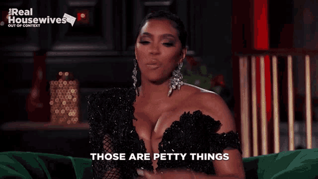 a woman in a black dress is sitting on a green couch and saying those are petty things