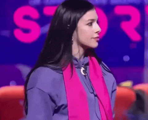 a woman wearing headphones and a pink scarf is standing in front of a sign that says s.