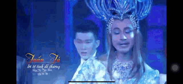 a man in a crown is standing next to another man in a white suit