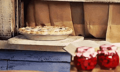 a pie is sitting on top of a stove next to jars of jam