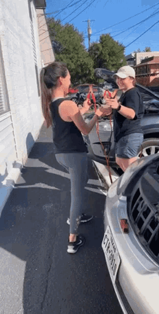 two women are standing next to a car that has a license plate that says gtr-3810