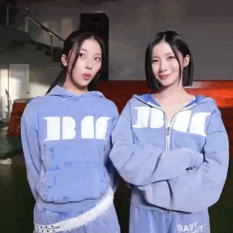 two girls in blue hoodies are standing next to each other .