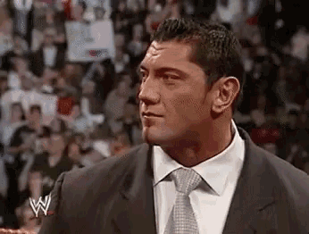 a man in a suit and tie is standing in front of a crowd in a ring .
