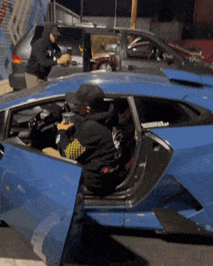 a man is sitting in a blue car with the door open