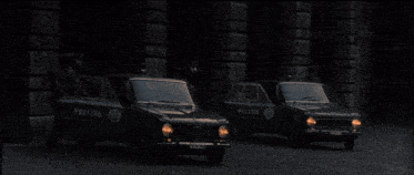 a man in a suit stands next to a car with a light on top of it