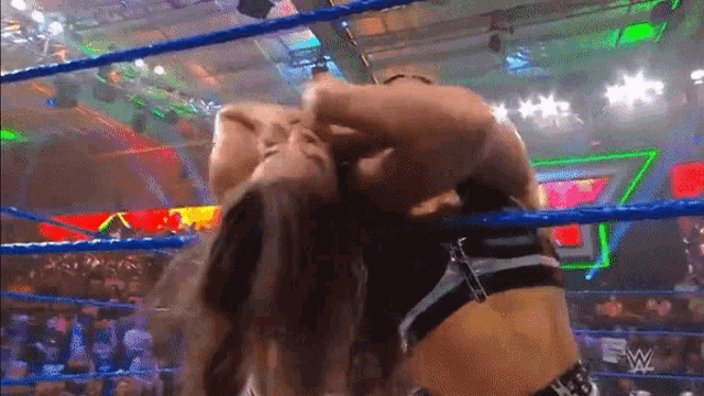 two women are wrestling in a wrestling ring and one is holding the other 's head .