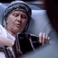 a woman is laying in a hospital bed with her eyes closed and a bandage on her arm .