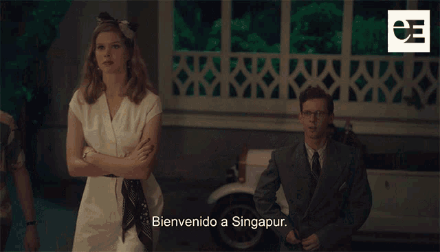 a man and a woman are standing in front of a car with the words bienvenido a singapur
