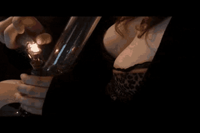 a woman in a leopard print top is holding a bong