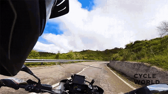 a person riding a motorcycle down a road with cycle world written on the bottom right