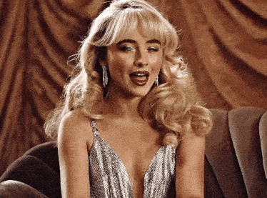 a woman in a silver dress is sitting on a couch and making a funny face .