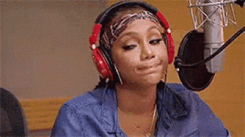 a woman wearing headphones is sitting in front of a microphone in a studio .