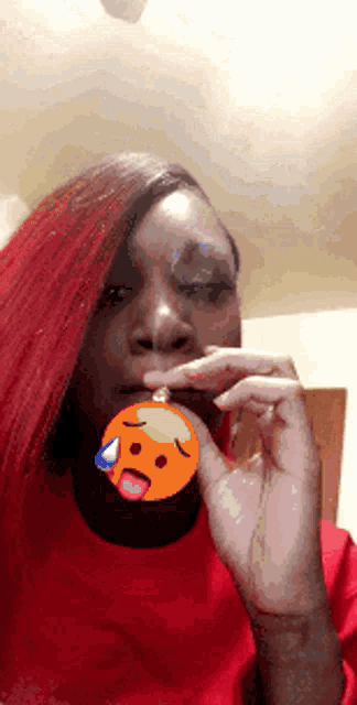 a woman with red hair is holding an orange smiley face