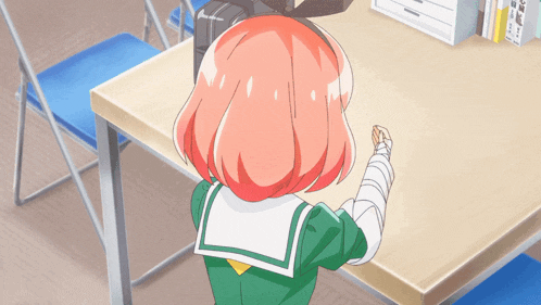 a girl with pink hair sits at a desk with a bandaged arm