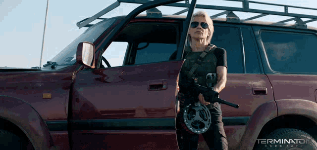 a woman is standing next to a red terminator car