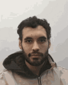 a man with a beard is wearing a jacket with a hood .