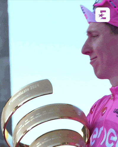 a man in a pink shirt holding a trophy that says classificato 2024