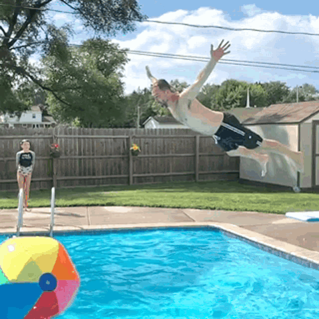 a man is jumping into a swimming pool while a woman watches