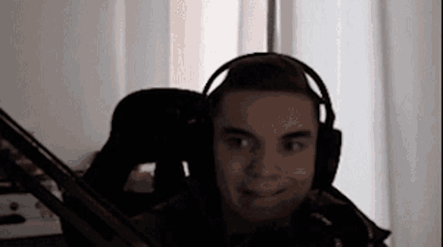 a man wearing headphones is sitting in a chair and smiling .