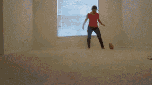 a woman in a red shirt is standing in a room with a window