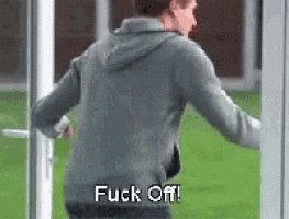 a man is standing in front of a door with the words `` fuck off '' written on his back .