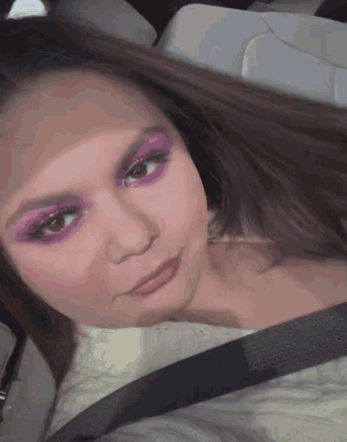 a woman with purple eyeshadow and a seat belt