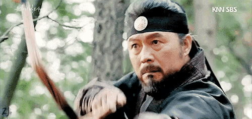 a man with a beard is holding a sword and wearing a headband that says kn sbs