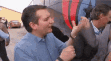 a man in a blue shirt is giving a high five to another man in front of a bus .