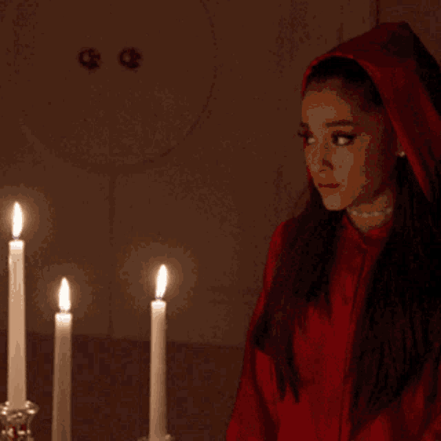 a woman in a red hoodie stands in front of candles