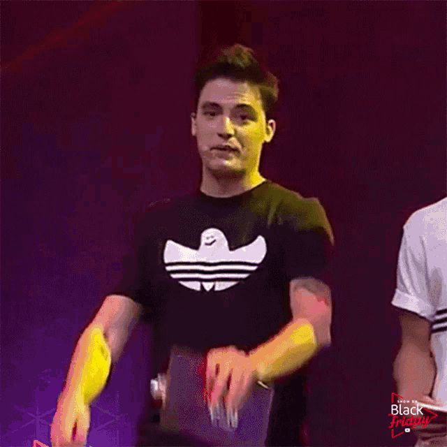 a man wearing an adidas t-shirt points at the camera