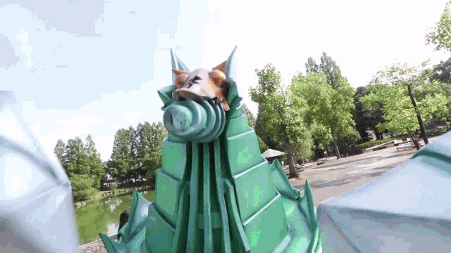a statue of a dragon is standing in a park with trees in the background