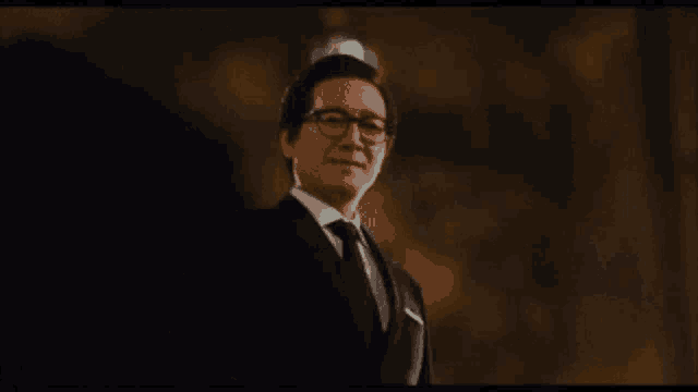 a man in a suit and tie is smiling with a crown on his head .