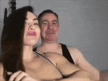a man and a woman are making funny faces while sitting on a bed .