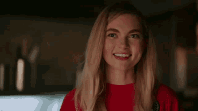 a close up of a woman in a red shirt smiling .