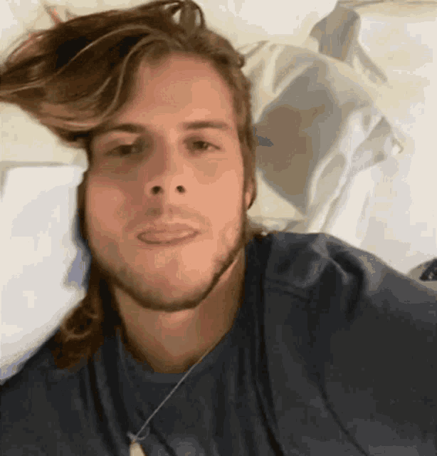 a man with long hair is laying on a bed