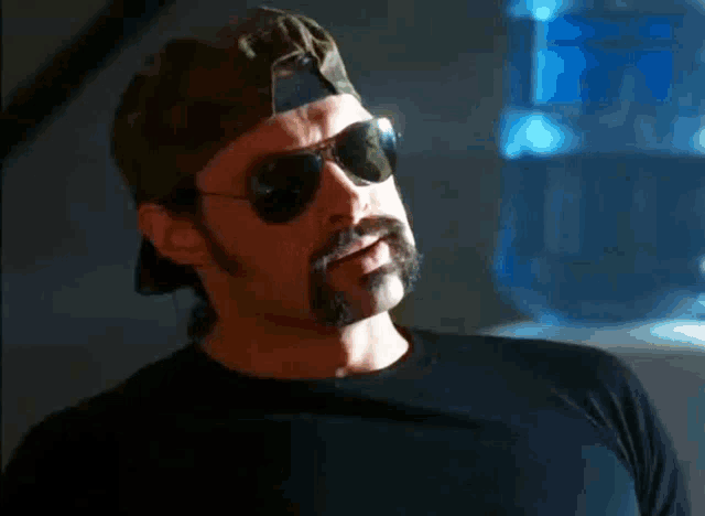 a man with a beard and sunglasses is wearing a baseball cap