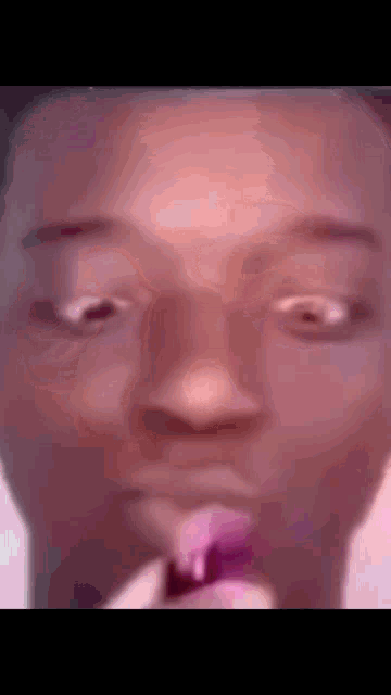 a close up of a person 's face with a pink object in their mouth