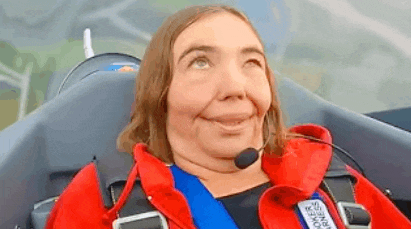 a woman is sitting in the cockpit of a plane with a microphone on her head .