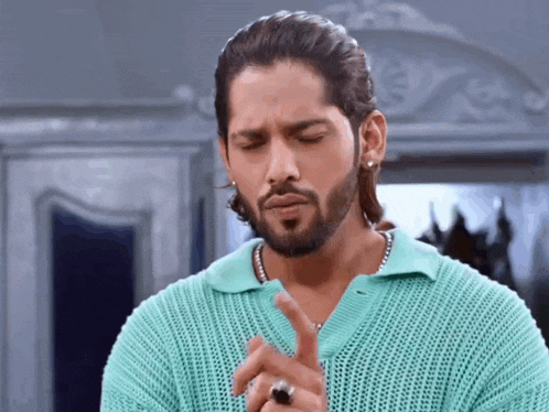 a man with a beard wearing a blue sweater and a ring on his finger