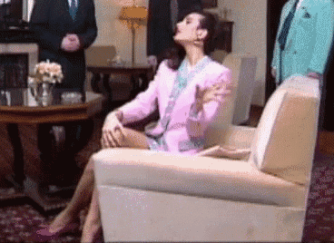 a woman in a pink suit is sitting on a chair