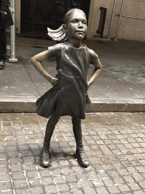 a statue of a little girl with her hands on her hips