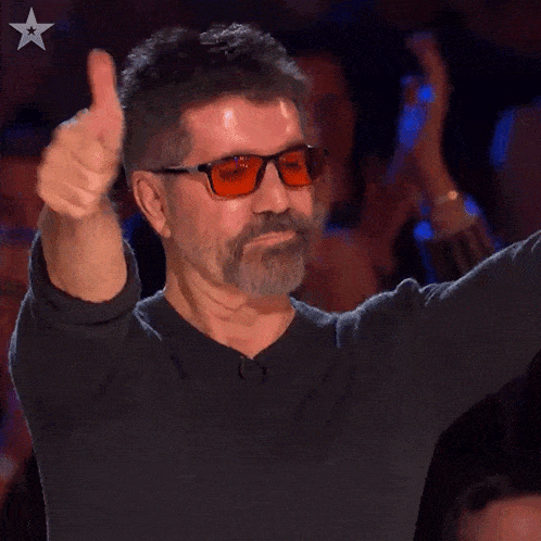 a man wearing glasses giving a thumbs up