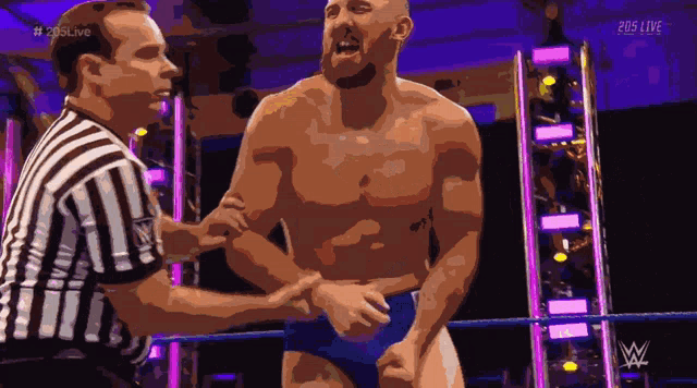 a shirtless wrestler is being helped by a referee during a 205 live event